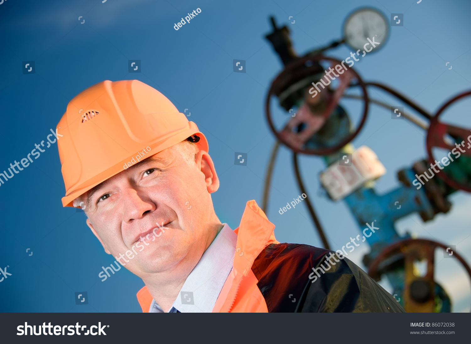 在橙色制服和头盔上的石油工人的阀门