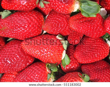 close up of bunch of large red berries strawberries with green