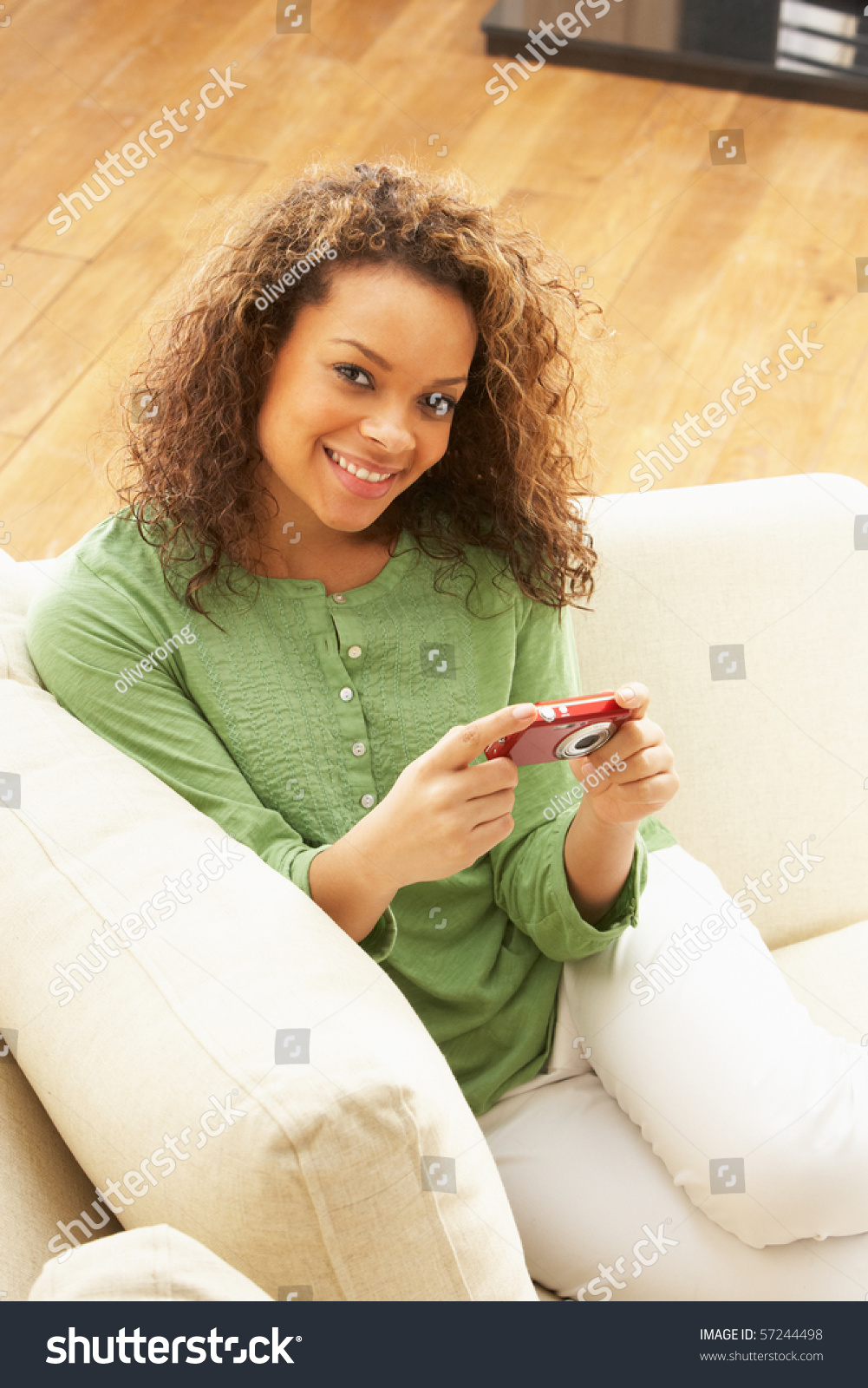 女人看着照片数码相机放松坐在沙发上在家里-科技,人物-海洛创意